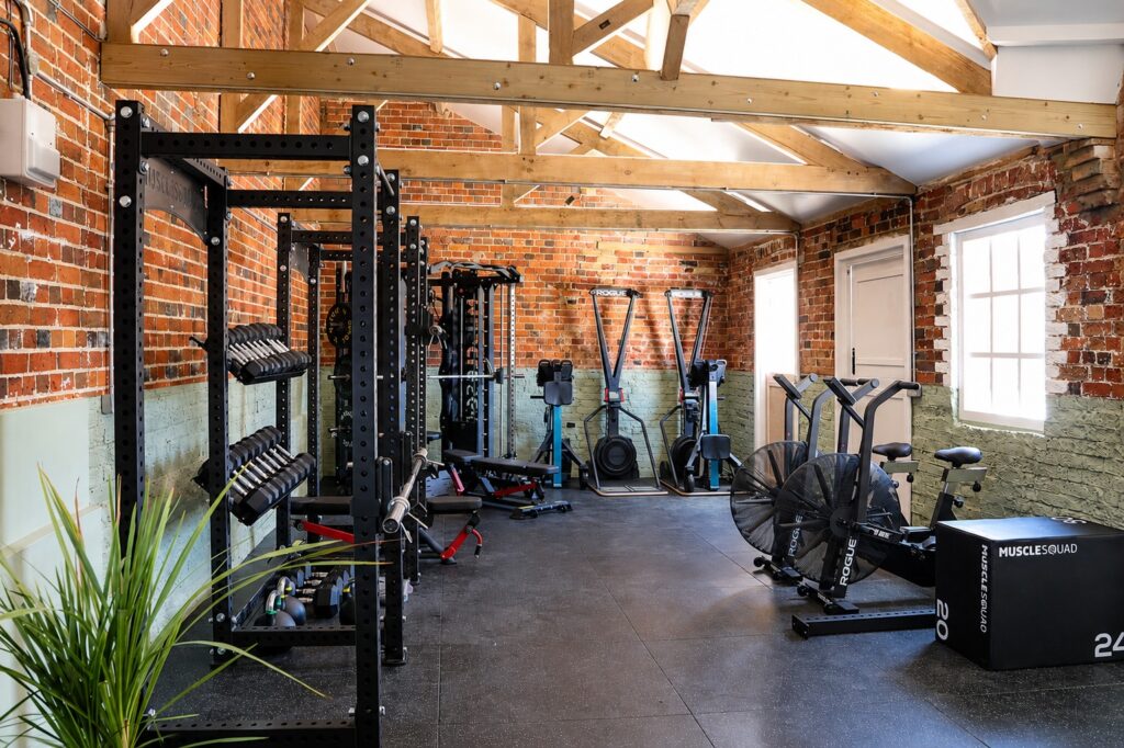 Inside The Stable Studio with strength and conditioning equipment beneath the converted stable beams